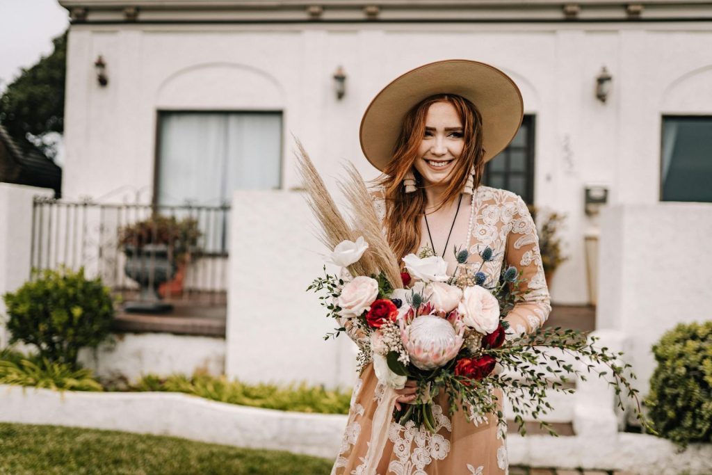 A Woman in Lace Dress Holding Bohemian Wedding Bouquet of Flowers